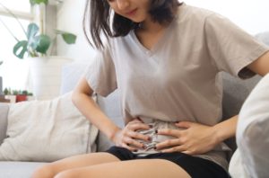 Young woman with hands on stomach experiencing anxiety and nausea