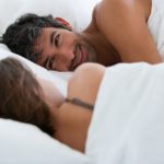 man in bed smiling overcoming erectile dysfunction caused by sexual performance anxiety