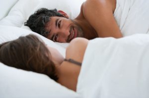 man in bed smiling overcoming erectile dysfunction caused by sexual performance anxiety