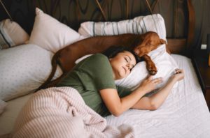 woman sleeping with vizsla dog after trying home remedies for insomnia