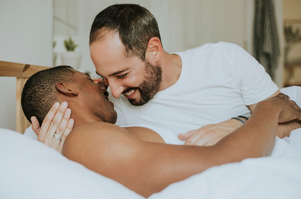 men in bed smiling after treatment for premature ejaculation symptoms
