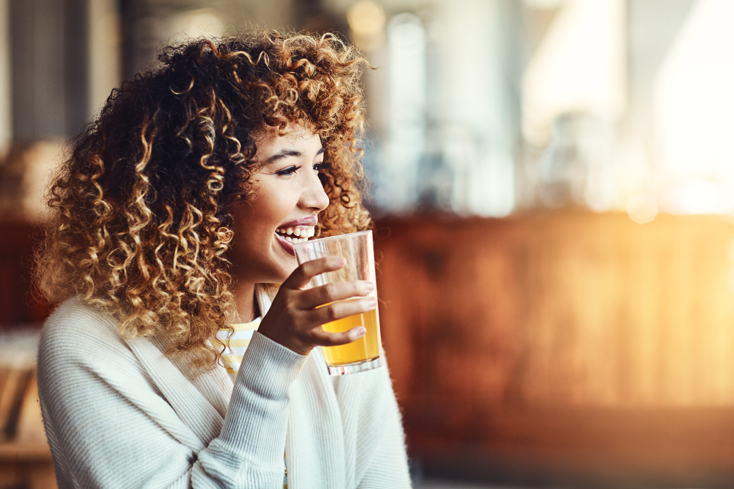 Image of a your woman holding a beer and smiling.