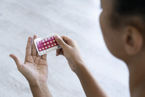 Young woman holding birth control pills looking down