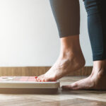 Close-up of a person’s feet stepping onto a bathroom scale, reflecting on of weight changes from informed choices about birth control.