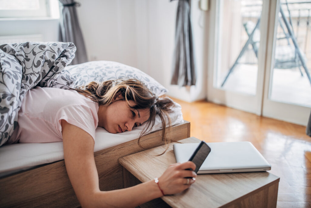 A young woman lying awake in bed, looking tired and sleepless, illustrating the impact of insomnia on daily life