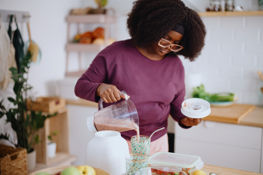 A woman in her kitchen pouring a homemade healthy smoothie symbolizing her natural dietary choice for managing her cholesterol levels