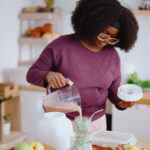 A woman in her kitchen pouring a homemade healthy smoothie symbolizing her natural dietary choice for managing her cholesterol levels