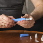 A man preparing an Ozempic® injection, illustrating the use of semaglutide for managing blood sugar levels, in the comparison between Ozempic® and Wegovy®