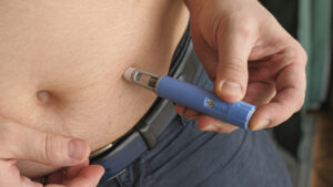 Overweight man administering a semaglutide (Ozempic®) injection, representing GLP-1 medications for blood sugar control and weight management