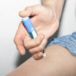 Person using an insulin injection pen to administer medication, illustrating diabetes management and the use of treatments like Ozempic®