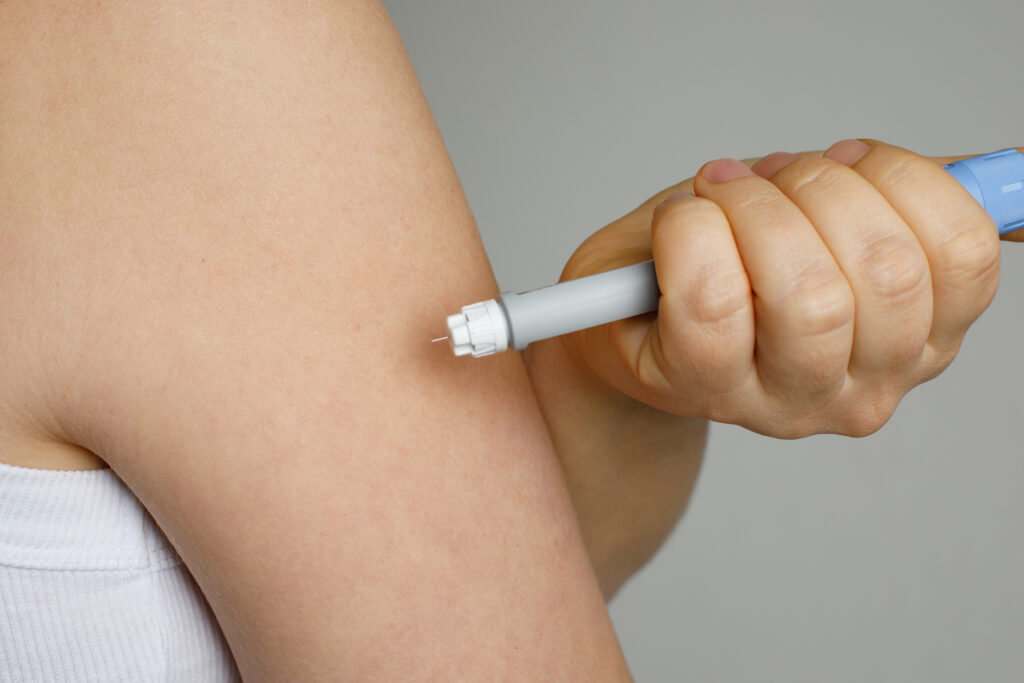 Close-up of a woman’s hand holding a self-injection pen, symbolizing the administration of GLP-1 medications.