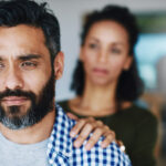 A man gazing with a contemplative expression while a woman offers support with her hand on his shoulder, representing empathy and the importance of support in understanding and managing depression