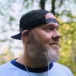 A bearded middle-aged man wearing a hat, representing the common concern about whether wearing hats can lead to hair loss, while emphasizing that myths about scalp circulation and hair health need to be clarified.