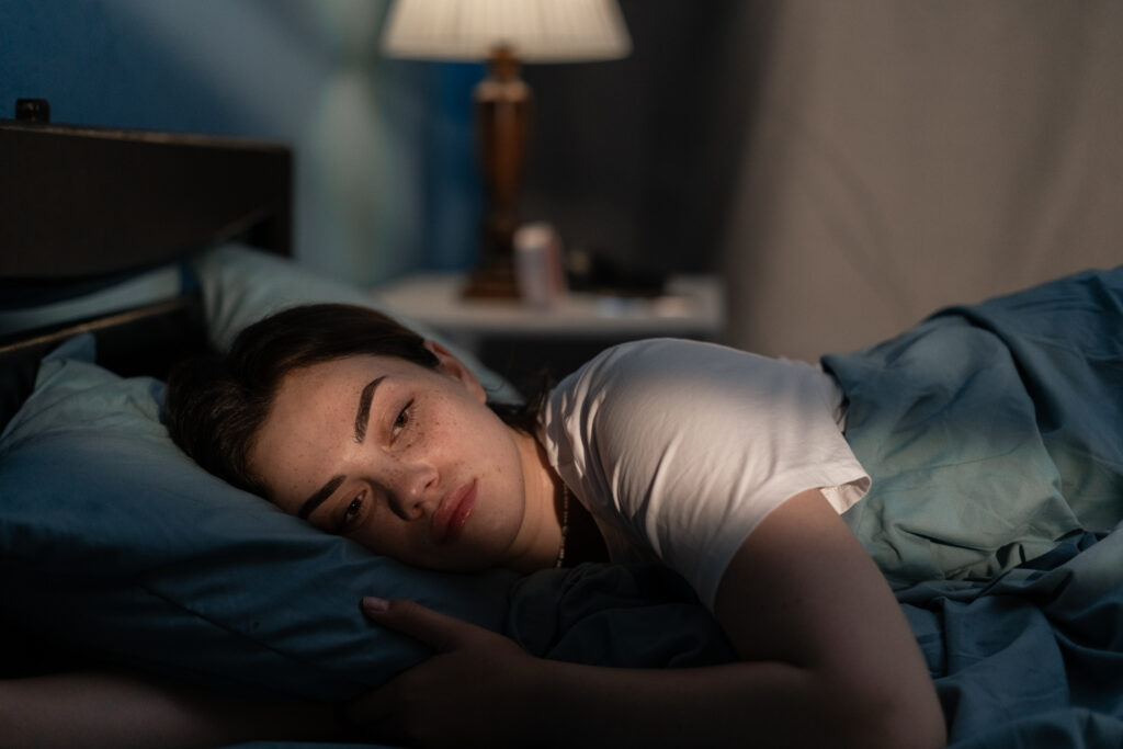 Woman lying in bed late at night, struggling to sleep due to insomnia, highlighting the importance of understanding the latest research on sleep disorders and treatment options.