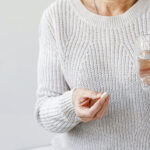 A woman holding a bupropion pill in her hand, representing the use of antidepressant medication for managing depression, seasonal affective disorder (SAD), and smoking cessation.