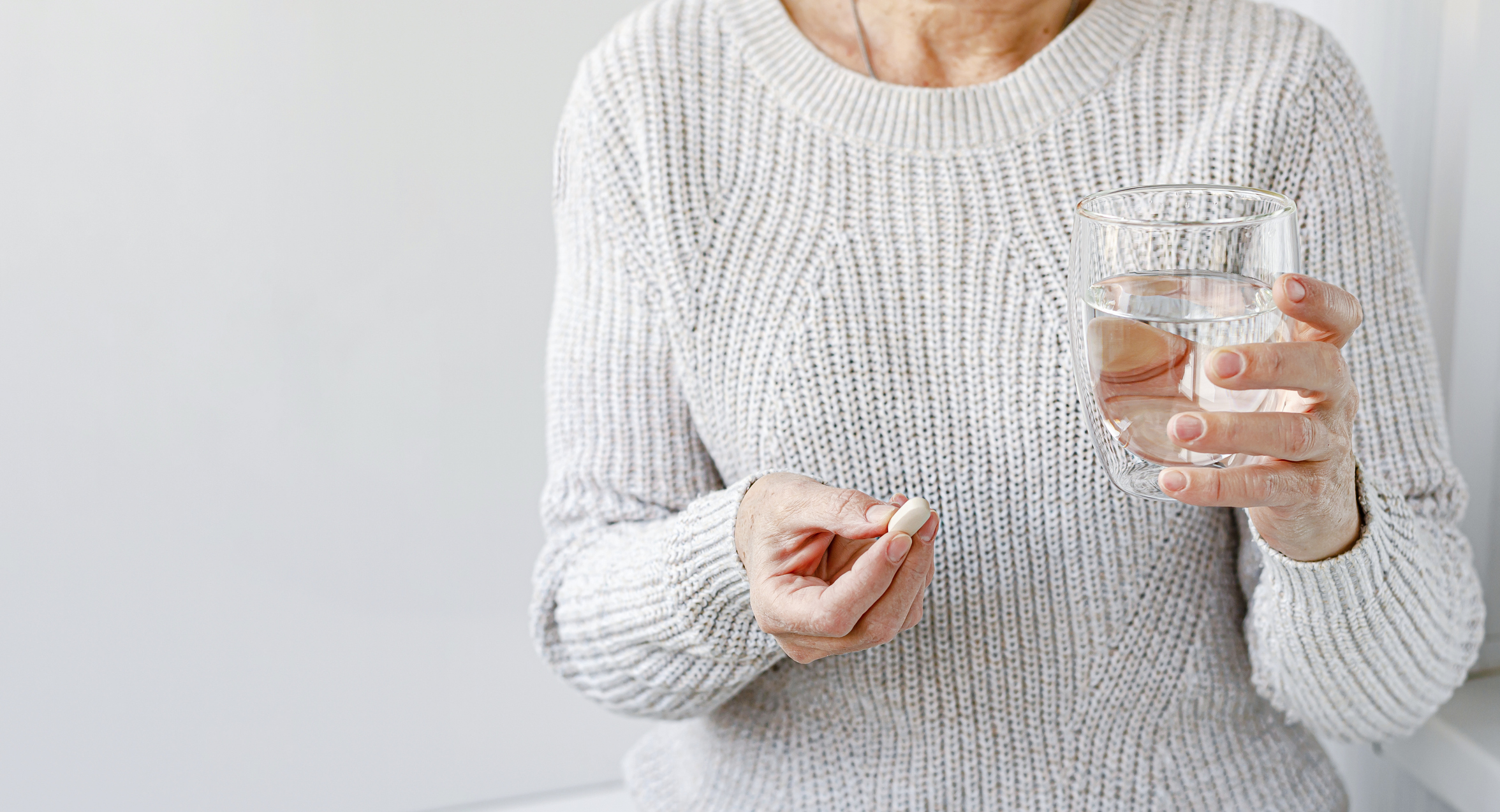 A woman holding a bupropion pill in her hand, representing the use of antidepressant medication for managing depression, seasonal affective disorder (SAD), and smoking cessation.