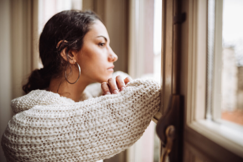 Woman looking out of the window, reflecting on misconceptions about obsessive-compulsive disorder (OCD), highlighting the importance of debunking common myths surrounding the condition.