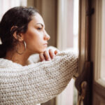 Woman looking out of the window, reflecting on misconceptions about obsessive-compulsive disorder (OCD), highlighting the importance of debunking common myths surrounding the condition.