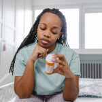 Woman reflecting the emotional challenges of managing mental health conditions like depression, holding a bottle of sertraline (Zoloft®) medication