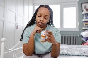 Woman reflecting the emotional challenges of managing mental health conditions like depression, holding a bottle of sertraline (Zoloft®) medication