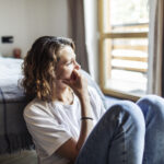 A woman sitting with her head in her hands, expressing stress and emotional distress, symbolizing the mental health struggles related to anxiety and depression.