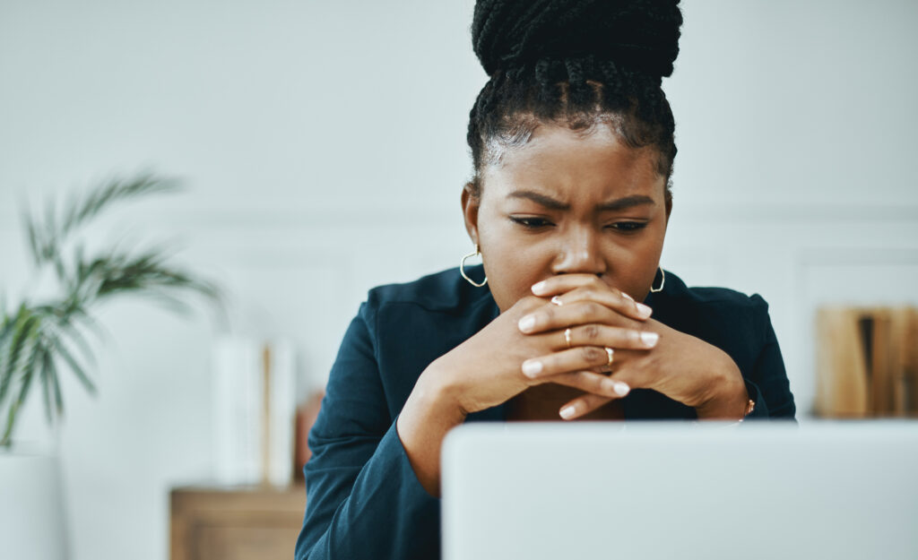 Businesswoman frowning while using a laptop, illustrating the internal struggle and challenges faced by individuals dealing with anxiety, often misunderstood as stress or weakness.