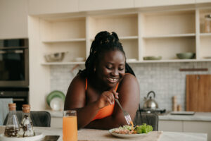 Woman eating a plate of healthy, balanced food with vegetables and protein, emphasizing the importance of sustainable weight loss through mindful eating and nutrition.