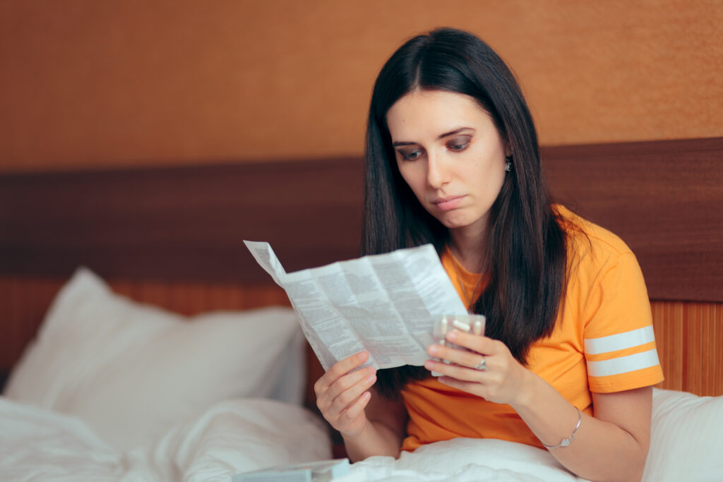 Woman reading medication instructions for Lexapro® (escitalopram) before taking the medication, highlighting the importance of understanding its side effects and safe usage.