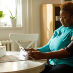 A woman checking her blood pressure at home, symbolizing the importance of monitoring and managing high blood pressure to prevent serious health risks.