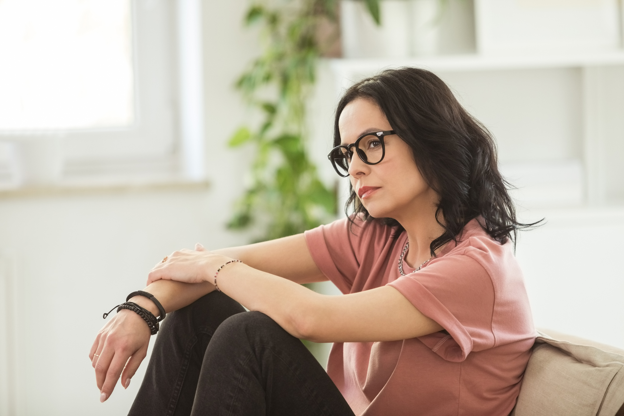 Concerned woman sitting on a couch at home, looking worried and thoughtful, reflecting the emotional challenges faced by individuals with mood disorders like depression and bipolar disorder.