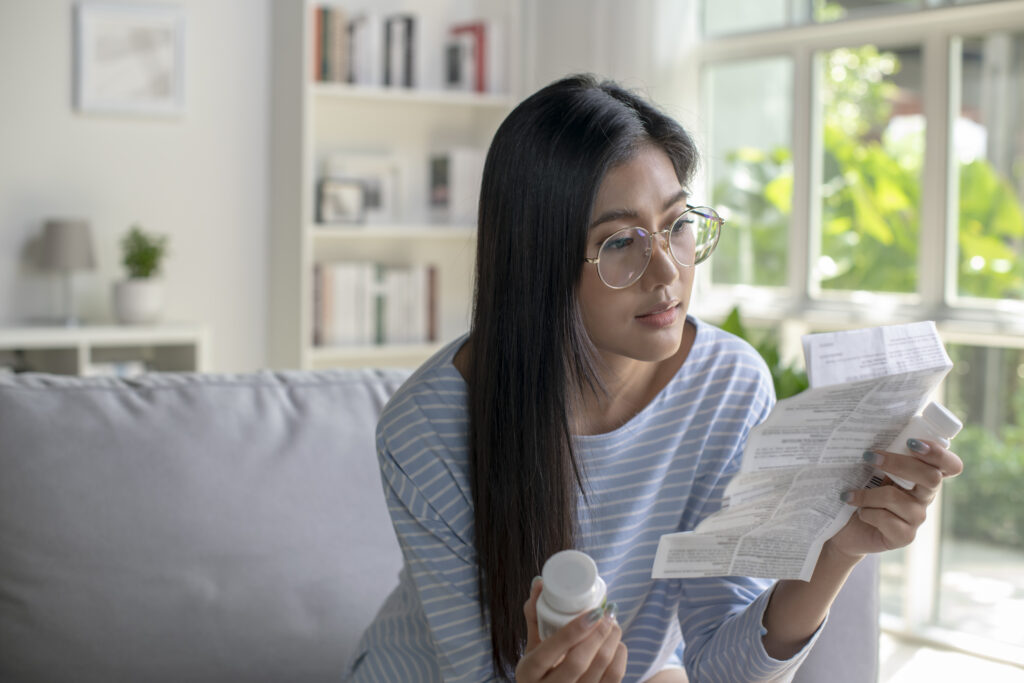 Woman reading Wellbutrin® instructions before taking her medication to better understand its side effects for depression treatment.