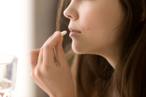 Close-up of a woman taking Zoloft® (sertraline) for treating depression, anxiety, and other mental health conditions.