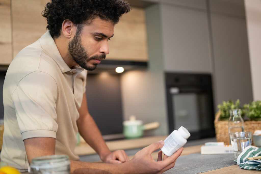 Man holding a bottle of Prozac® (fluoxetine), reading the label to understand its potential side effects.