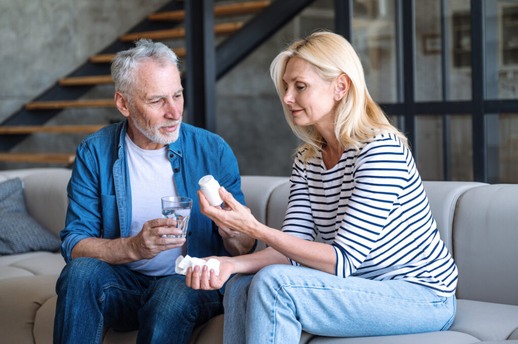 Man handing his wife her medication and a glass of water, symbolizing the supportive role of loved ones when starting Wellbutrin®.