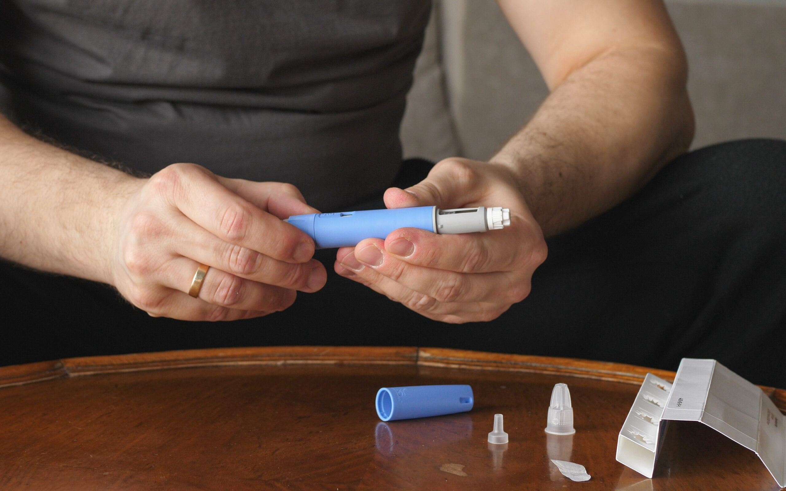 Man holding an injection pen for weight loss treatment, representing the use of GLP-1 medications like Wegovy® and Ozempic®.