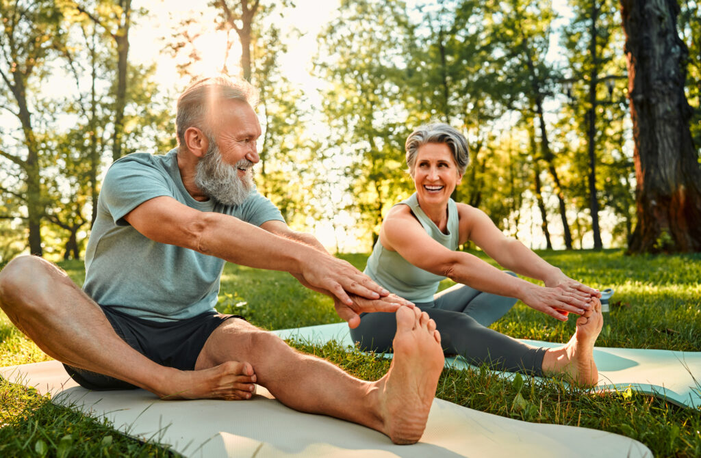 Man and woman stretching on a yoga mat outdoors, highlighting the role of a healthy lifestyle in supporting Cialis® effectiveness.