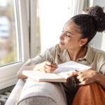 A woman writing notes in a notebook, symbolizing the reflective process of therapy to identify emotional triggers and support weight loss goals.