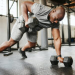 Bald male lifting dumbbells in the gym, illustrating the potential impact of finasteride on testosterone levels.