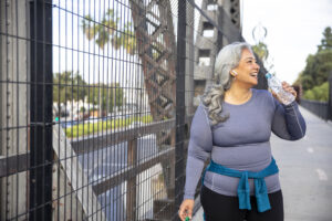 A woman drinking water after exercise, symbolizing the role of physical activity in supporting a medical weight loss plan for overall health and well-being.