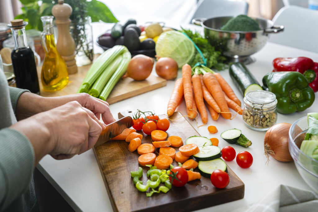 A woman cutting fresh vegetables on a kitchen counter, emphasizing the role of nutrition in medical weight loss programs and healthy meal preparation.