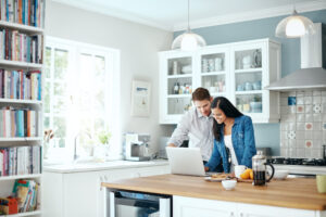 Couple in the kitchen researching on their laptop to better understand the potential side effects of Prozac®.