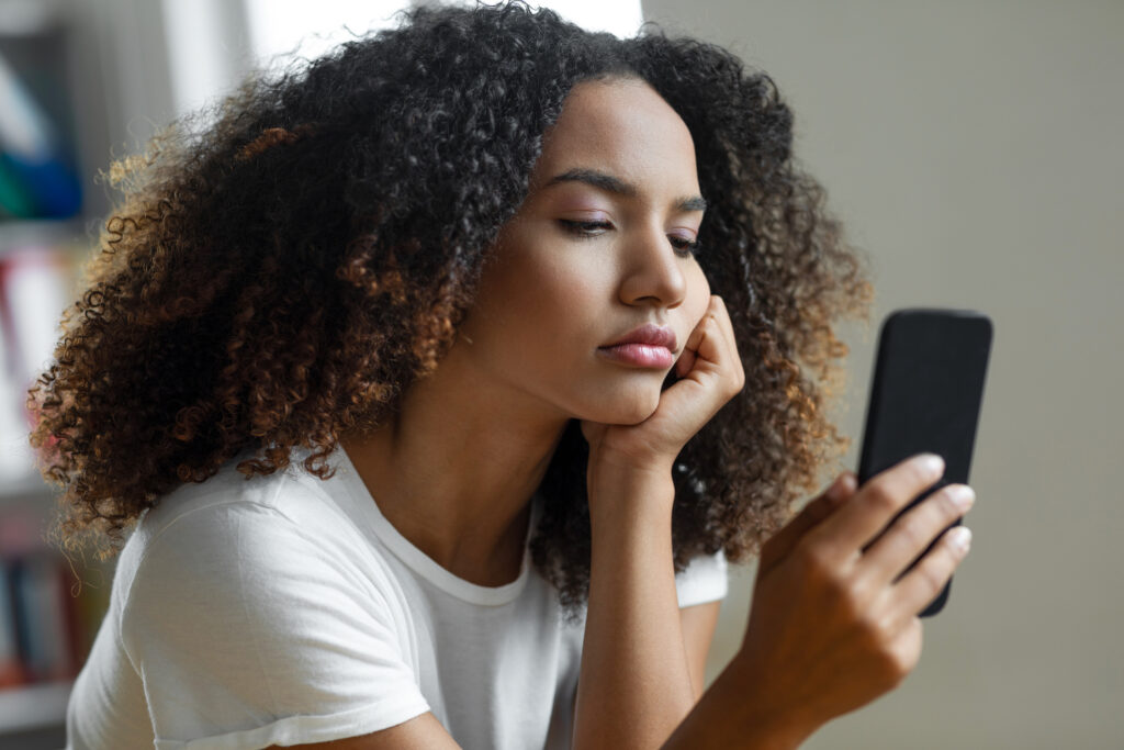 Woman looking at her cell phone, researching symptoms to determine if they are normal when stopping Wellbutrin®.