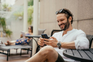 Man researching on his phone while relaxing by the pool, emphasizing the importance of understanding the guidelines for alcohol consumption when taking medications like Stendra® to ensure safety.