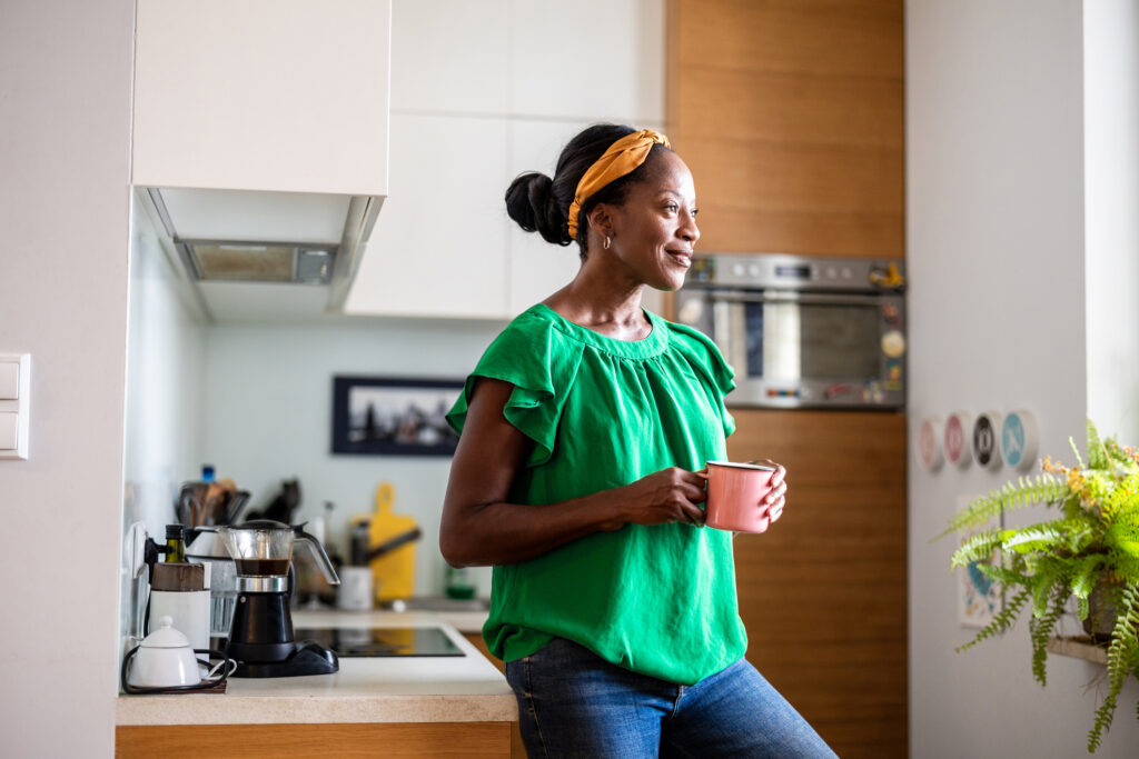 A middle-aged woman standing in her kitchen, reflecting on how to safely navigate reproductive health choices over 35