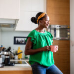 A middle-aged woman standing in her kitchen, reflecting on how to safely navigate reproductive health choices over 35