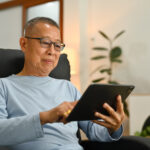 A man relaxing while using his tablet to research treatment options for erectile dysfunction.