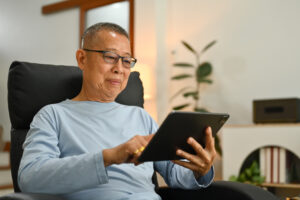 A man relaxing while using his tablet to research treatment options for erectile dysfunction.