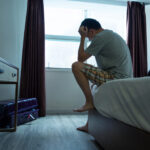 A man sitting on the bed with his head in his hands, reflecting the frustration and concern felt by experiencing premature ejaculation.