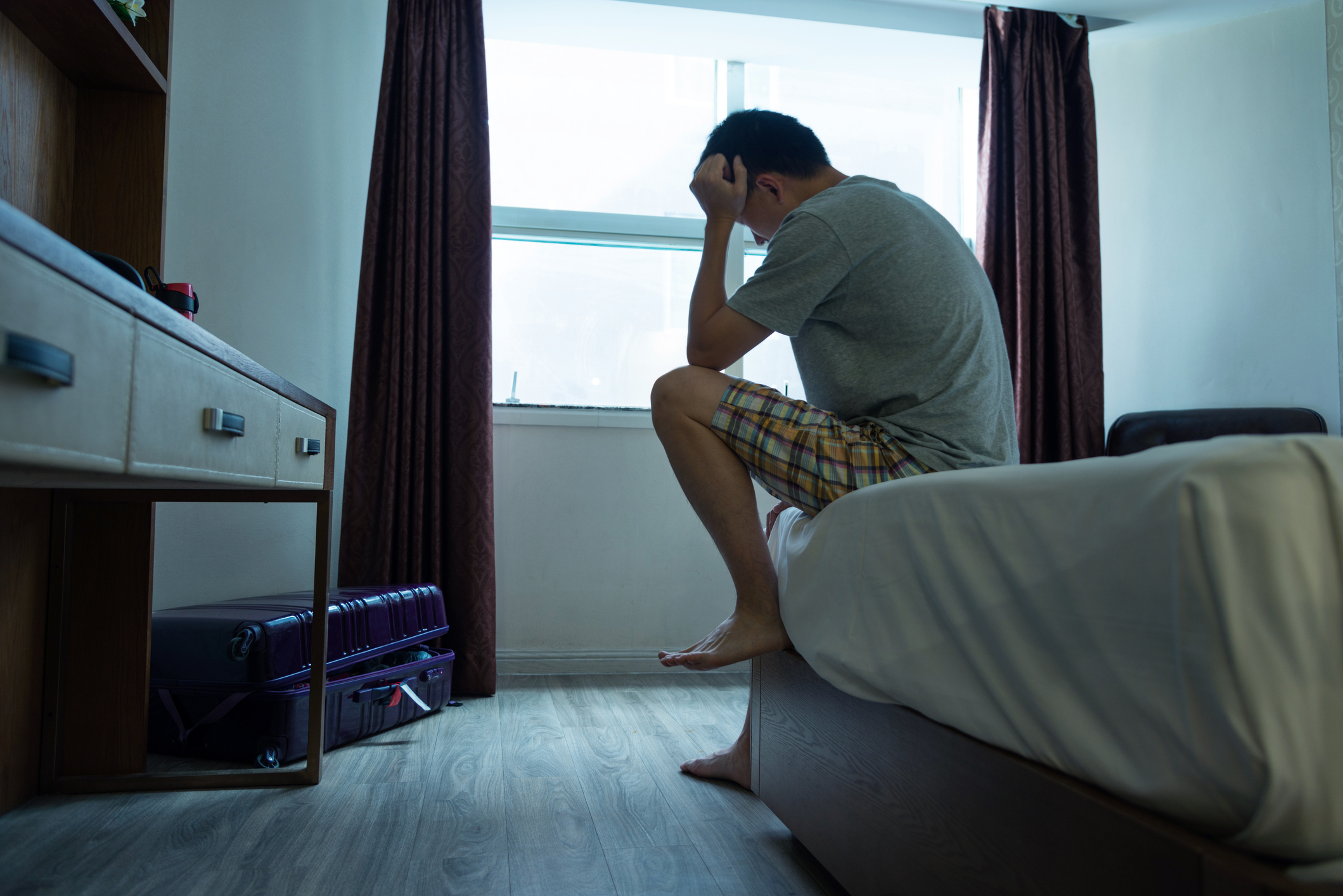 A man sitting on the bed with his head in his hands, reflecting the frustration and concern felt by experiencing premature ejaculation.