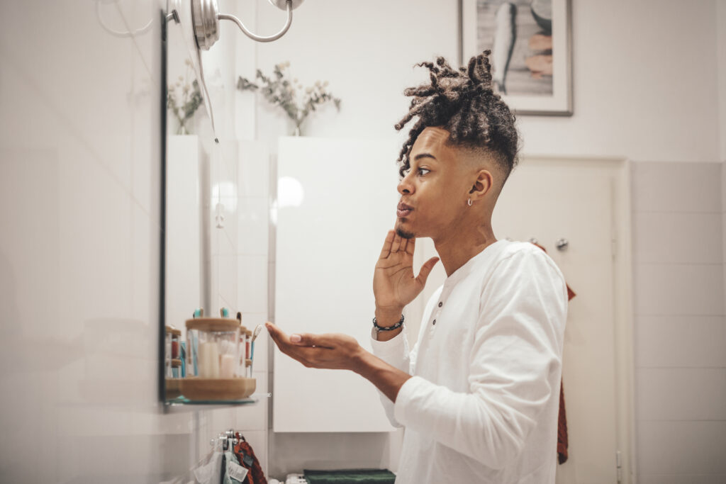 Man in the bathroom washing his face, symbolizing the importance of daily skincare and the use of acne medications for clearer skin.